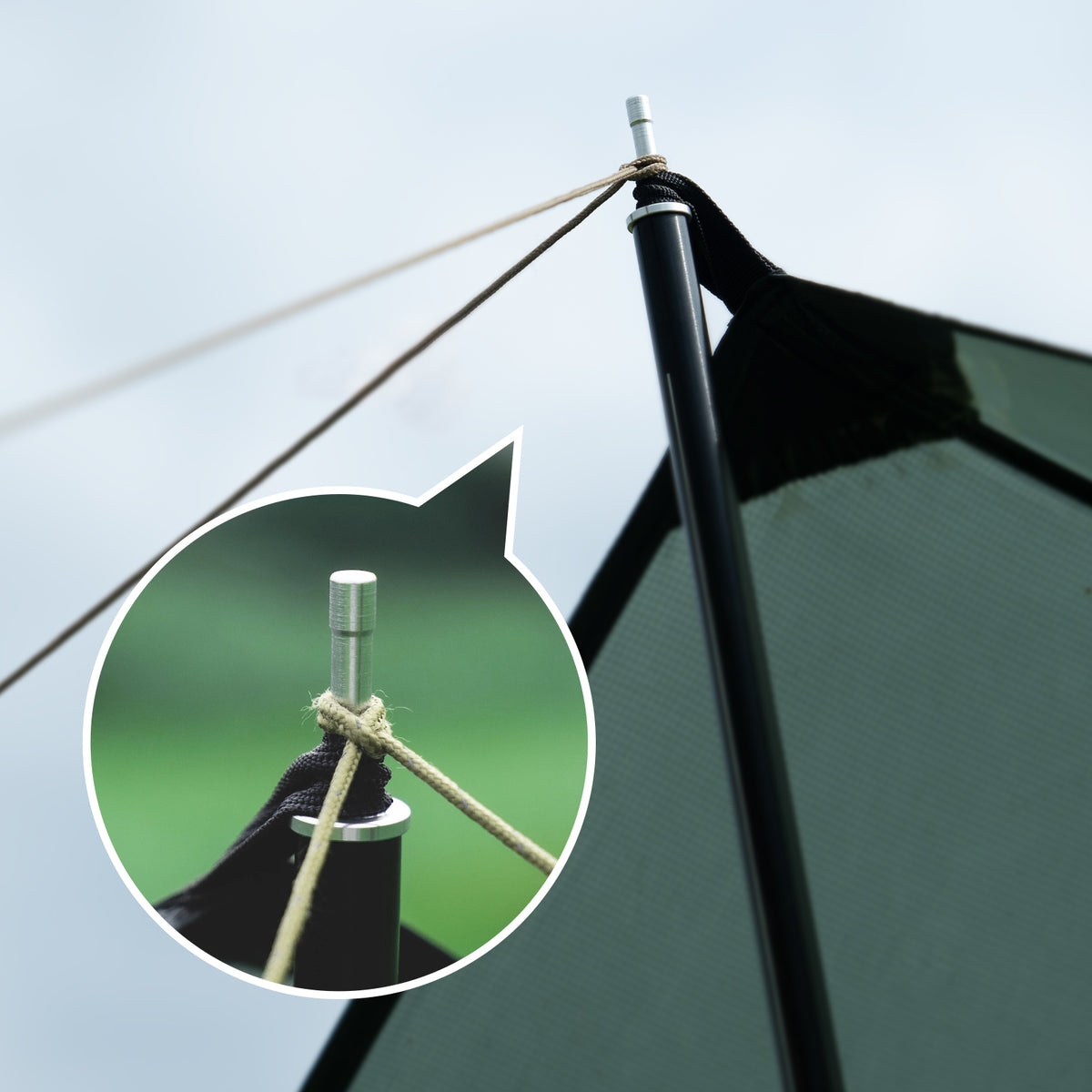 Close-up of a black flagpole with rope and metal fitting against a clear sky.