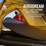 Aerodream self-inflating mattress displayed in front of a yellow tent with a person peeking out.