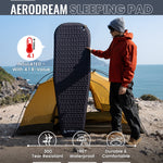 Person holding an Aerodream sleeping pad with camping scene and product features displayed.