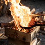 Wooden spoon over a campfire on a metal stove