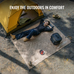Person lying on a camping mat next to a yellow tent with text 'Enjoy the Outdoors in Comfort'.