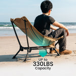 Person sitting on a portable chair on a beach with text indicating weight capacity.
