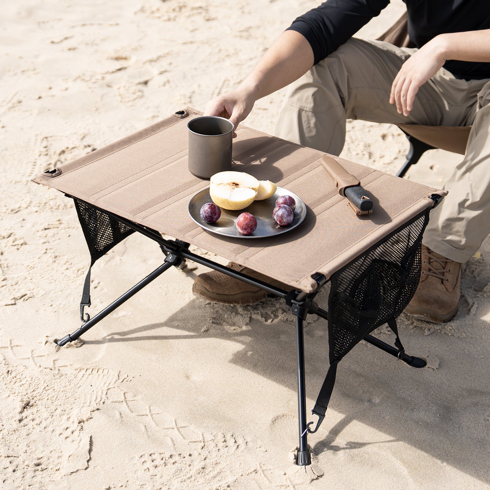 Portable camping table with food on a sandy surface