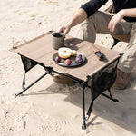 Portable camping table with food on a sandy surface