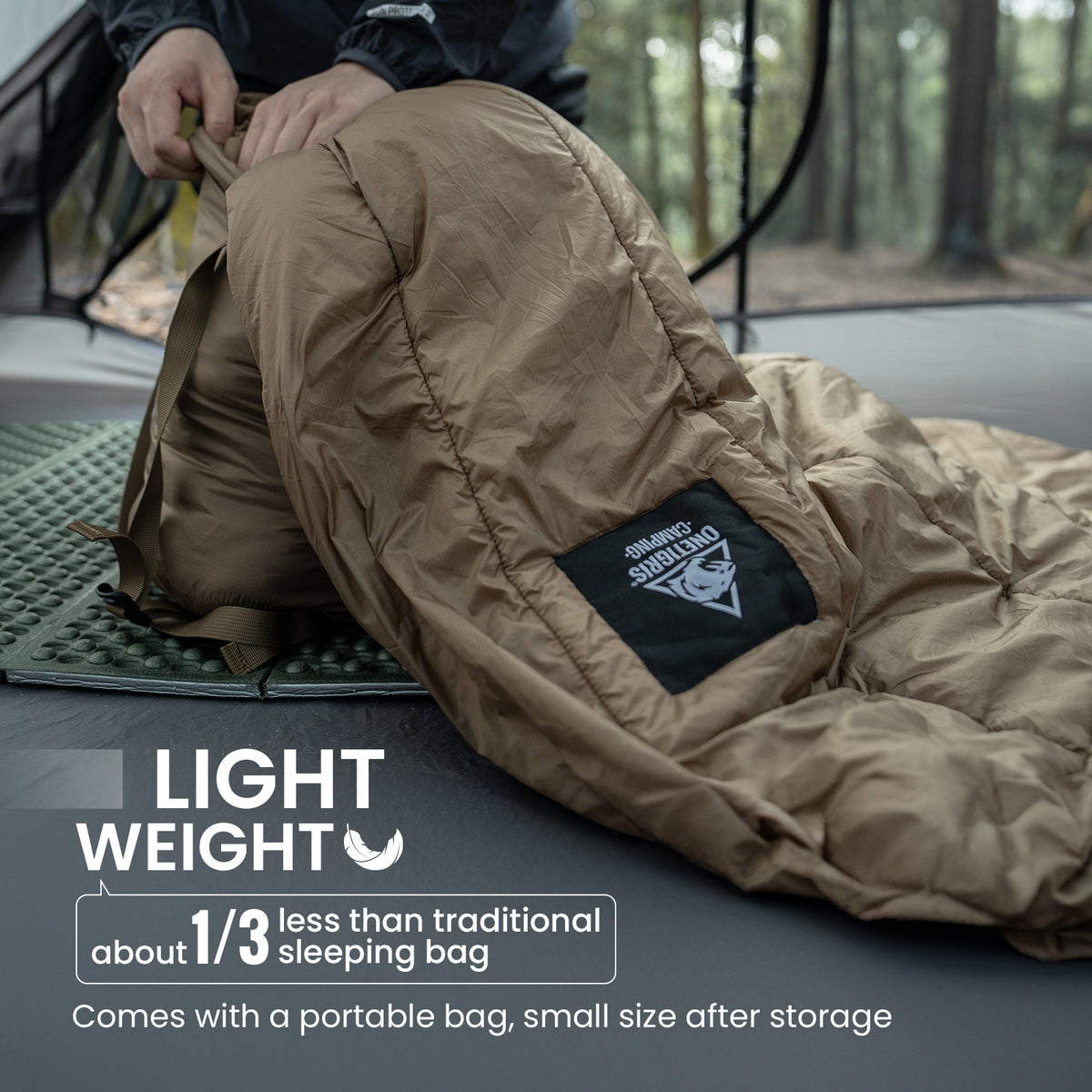 Brown sleeping bag with a brand logo on a camping surface, surrounded by a forest.