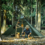 Person camping in a forest with a tent and cooking equipment.