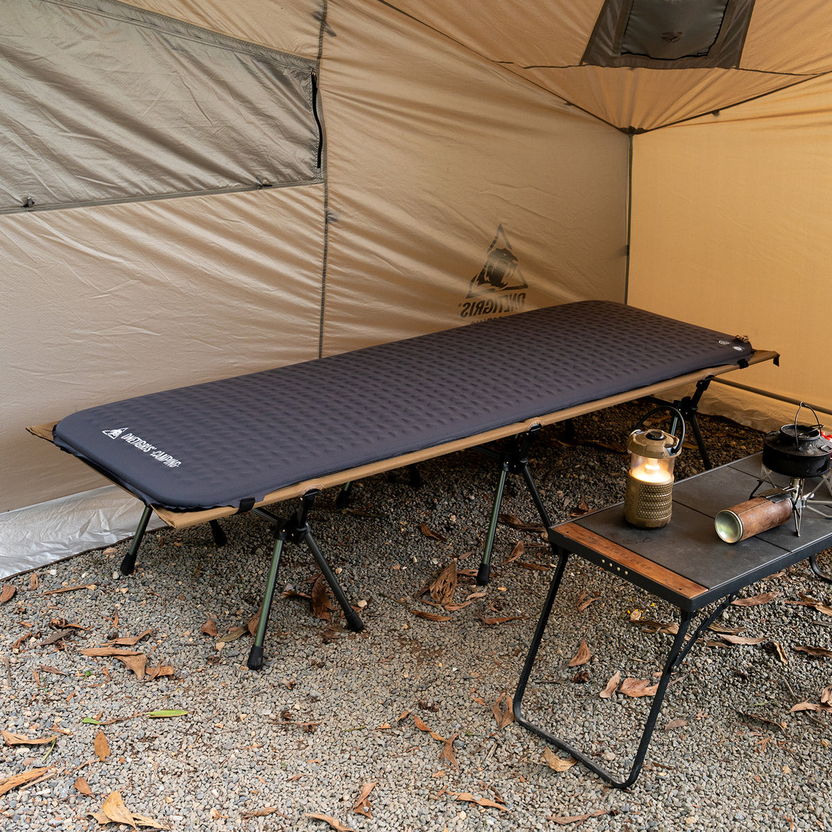An inflatable mattress suitable for folding beds, inside a tent with a small table and lantern nearby.